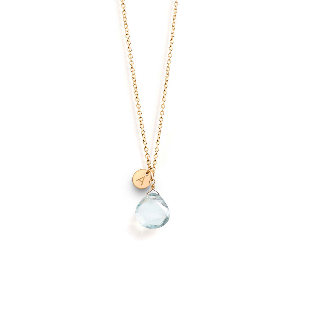 The March Aquamarine Birthstone Necklace features a blue aquamarine gemstone on a fine gold chain, personalised with a tag with an 'A' initial. Designed and handcrafted in our Devon studio.