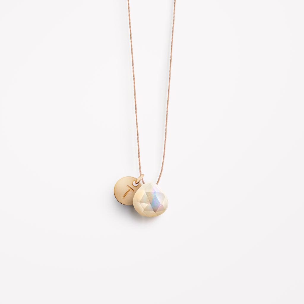 Personalised with a T initial on a gold disc, the mother of pearl fine cord is an opaque, white and iridescent gemstone, reflecting the magic of the sea. Our signature fine cord necklaces are minimal and modern and can be personalised for an extra element of meaning.