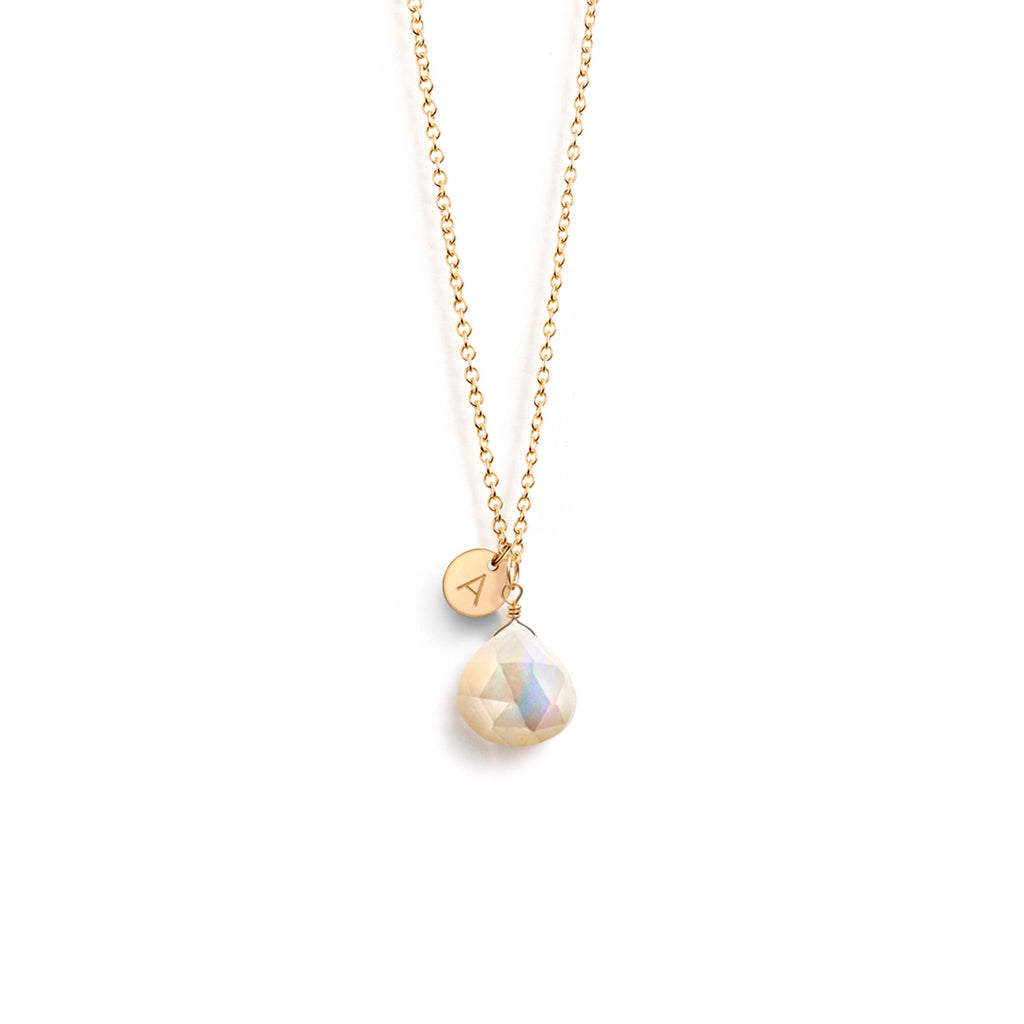 Personalised with an A, a gold disc charm hangs beside a mother of pearl gemstone. Choose your initial to create a personalised, monogram gemstone necklace.