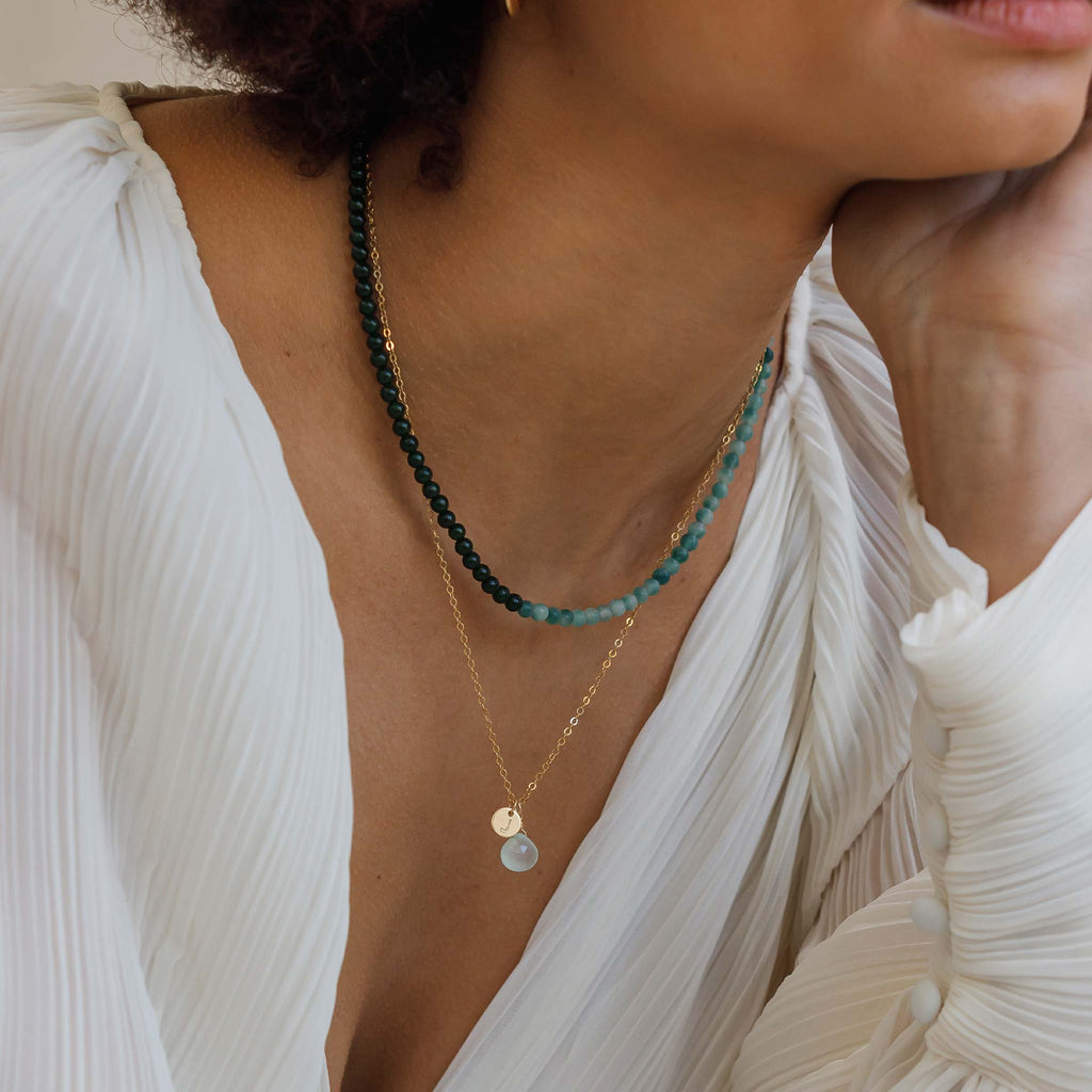 Persoanlised with a hand-stamped initial tag, the sea glass chalcedony pendant necklace is a gemstone necklace in a cloudy hue of green and blue, with the texture and appearance of sea glass. Create a personalised necklace and choose your initial.