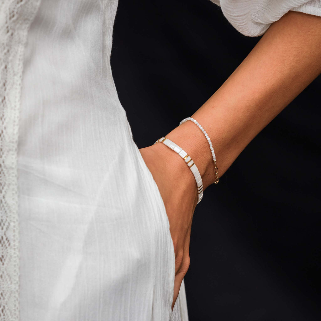 A beaded bracelet provides accents of shimmering white and gold on a fine elasticated band.