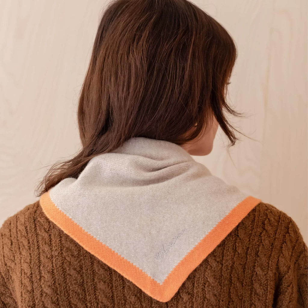 Model wears camel colour triangle scard with orange border