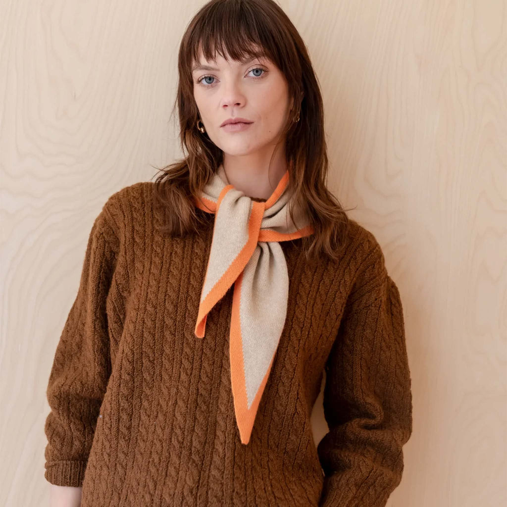Woman wearing TBCo camel triangle scarf with apricot orange border.