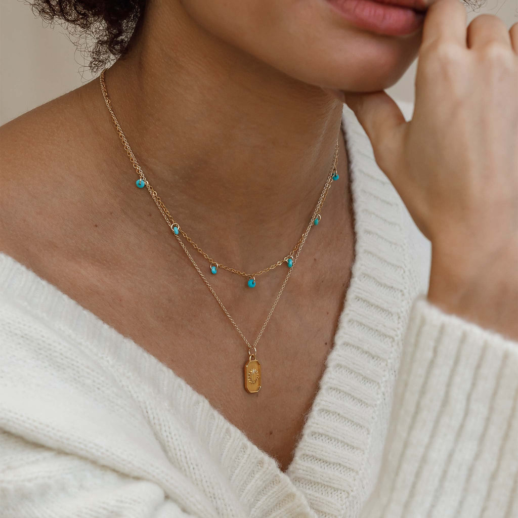 The turquoise Telltale necklace is a short layering chain, featuring faceted turquoise beads placed like charms hanging from the chain/
