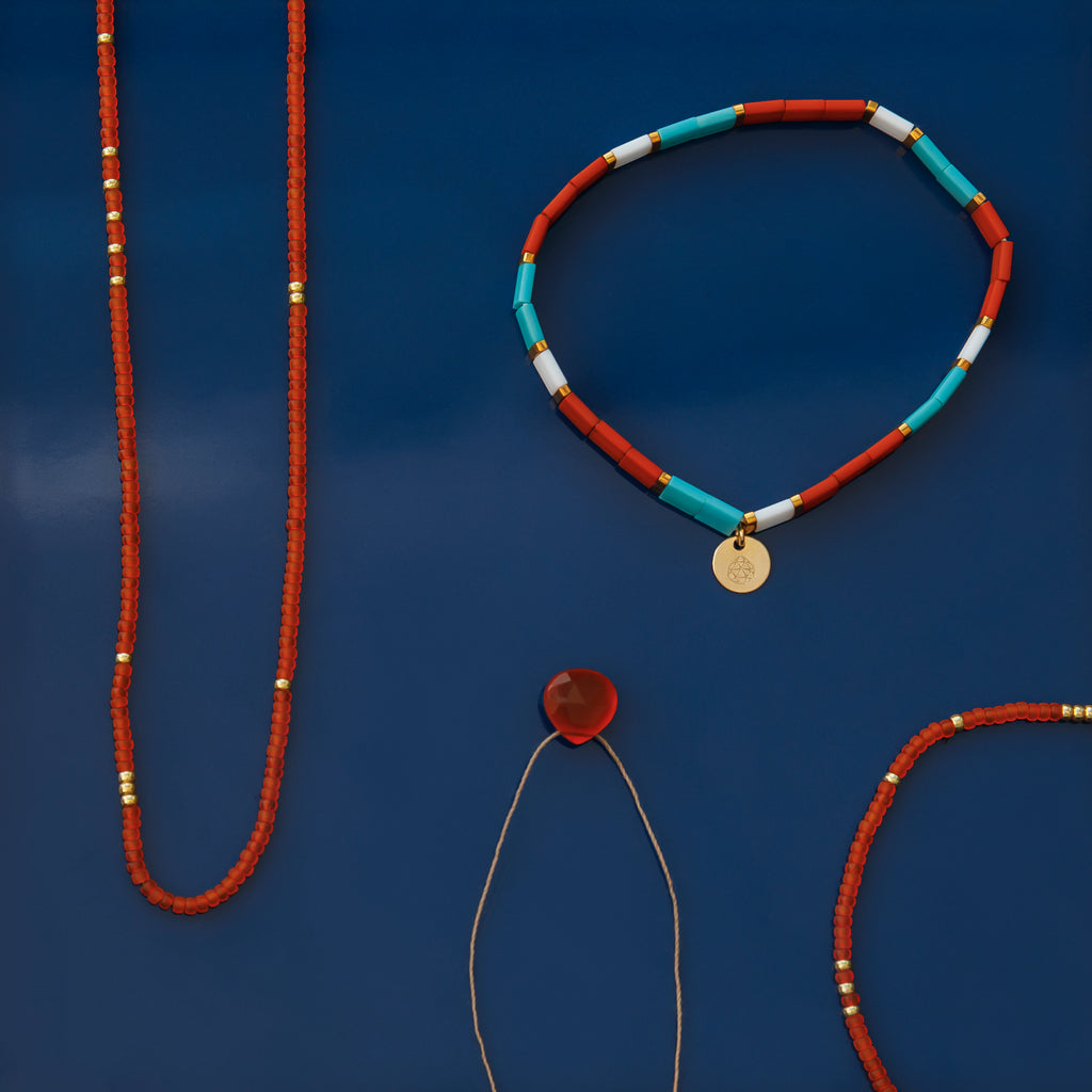 The Orange Carnelian Fine Cord Necklace is flat laid alongside the Orange Tangiers beaded necklace and Tila bead Safi Layering Bracelet.
