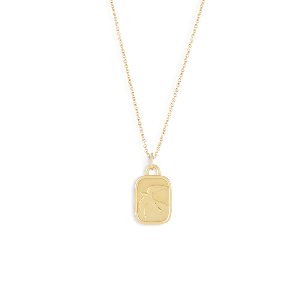 A lozenge shaped brushed gold vermeil pendant is adorn with a swallow in flight, symbolising the elemental air sign.