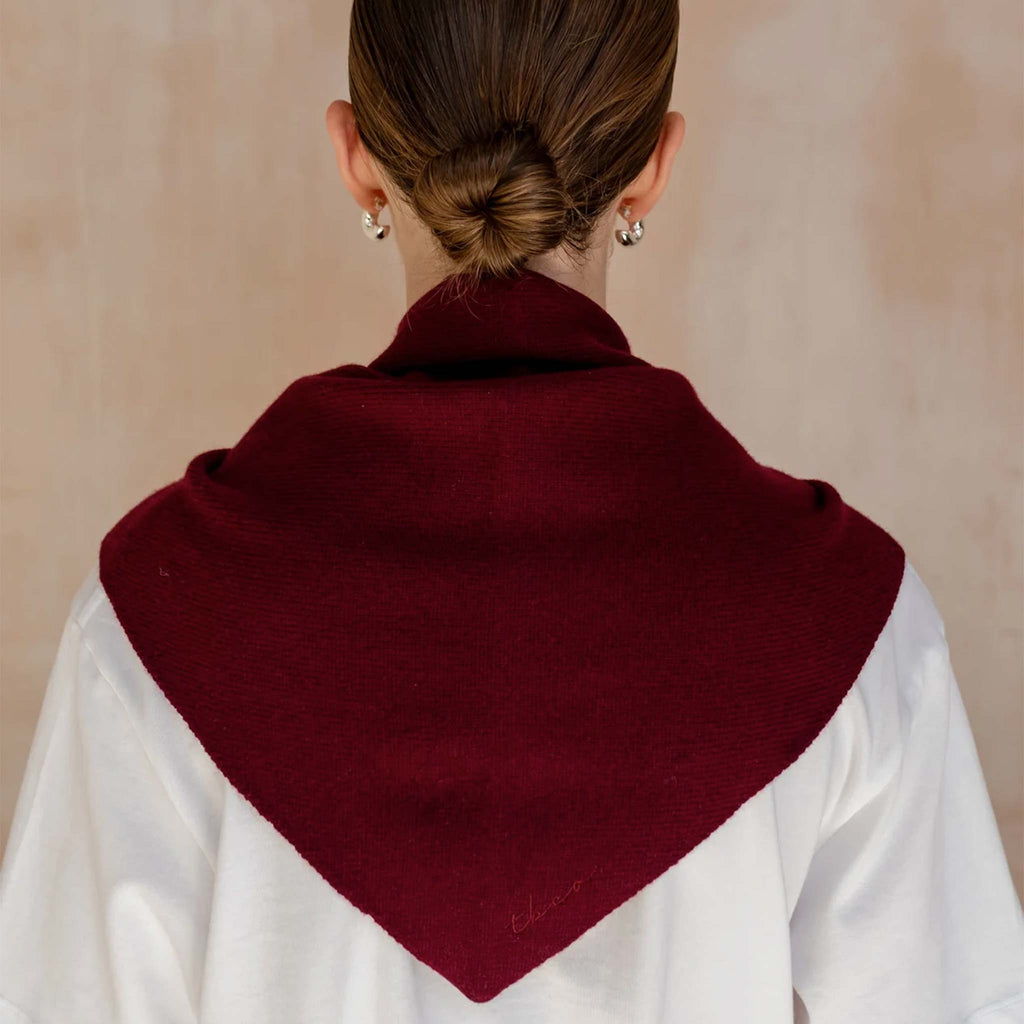 A burgundy triangle scarf knitted from 100% merino wool.