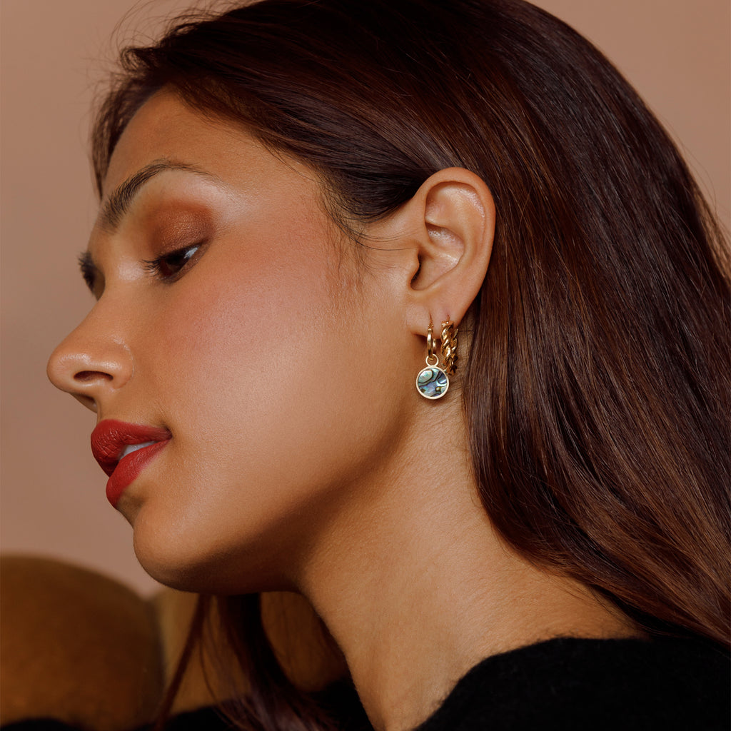 A glowing slice of paua shell is framed in brushed gold to create these bestselling portilla hoop earrings. Worn with chubby twisted hoop earrings.
