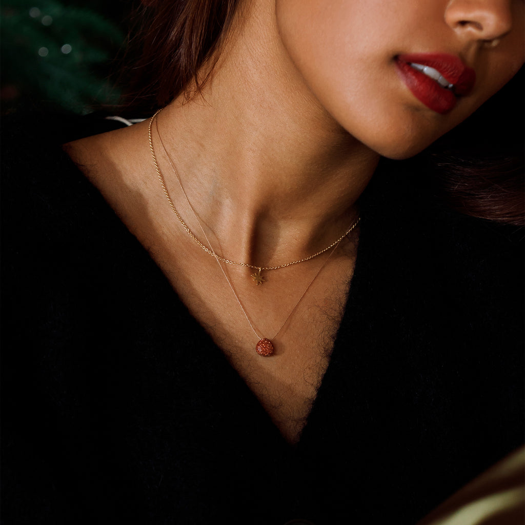An easy-to-wear star pendant hangs from a delicate chain, styled layered with a goldstone fine cord necklace.