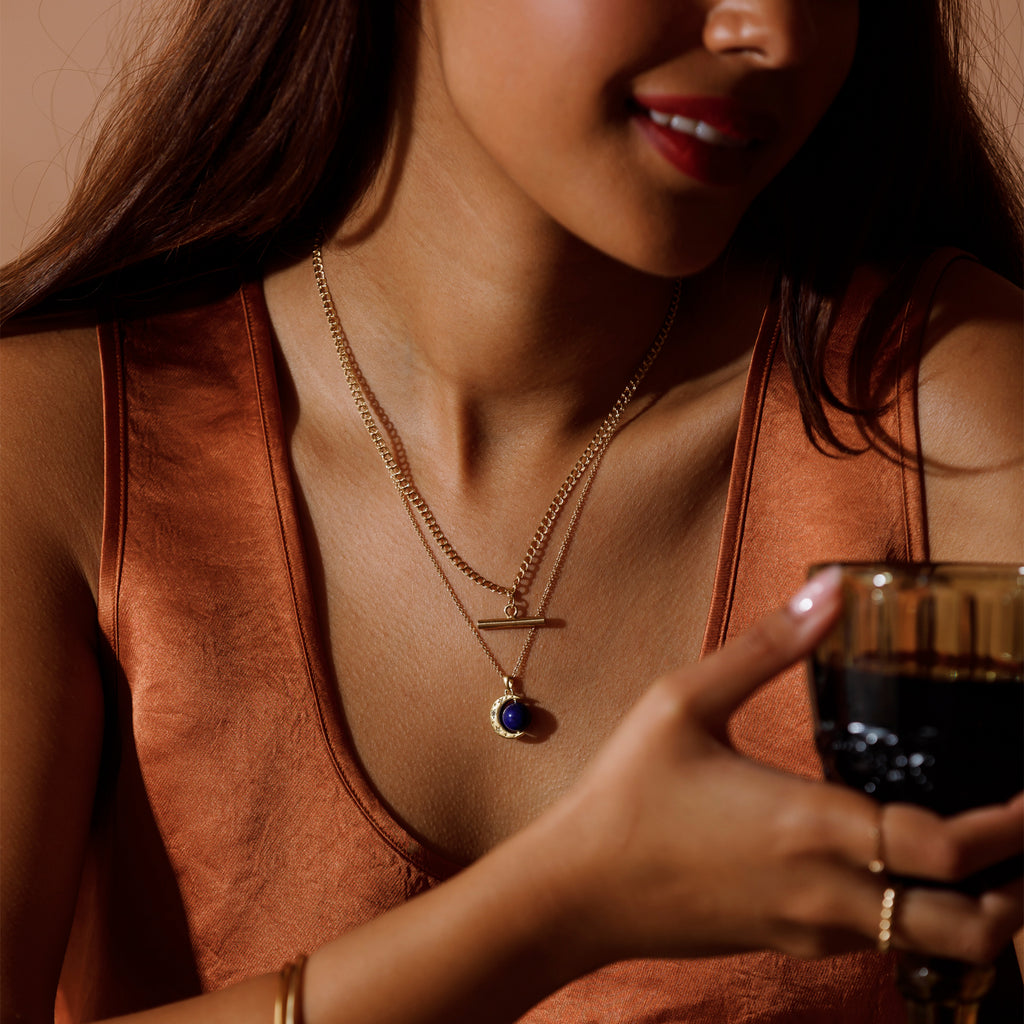 Model wearing a gold necklace layering stack featuring Megan Double Curb Toggle Necklace and Lapis Lazuli Earth Spinner necklace.