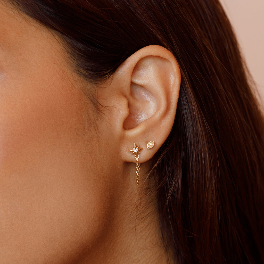 Ear stack of Topaz Vega Star Stud Earring worn with a White Topaz Elliptical Stud Earring.