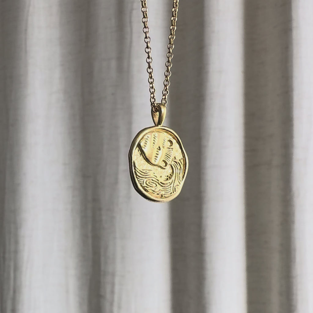 Video of Aquarius Zodiac Pendant Necklace moving against a fabric background.