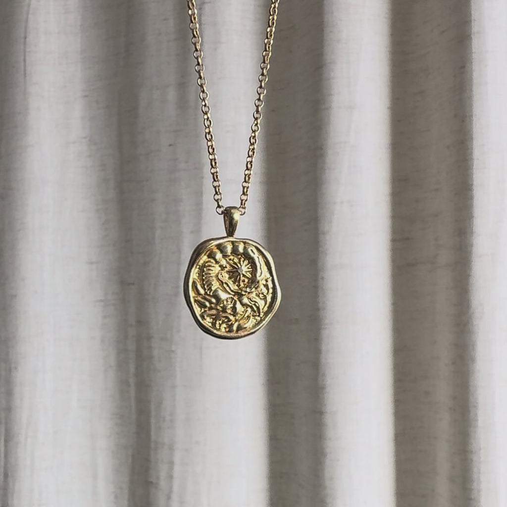Video of Scorpio Zodiac Pendant Necklace moving in the sun against a natural fabric background.