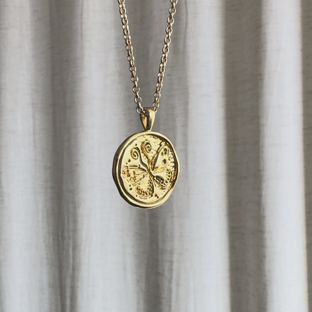 Video of Gemini Zodiac Pendant Necklace moving in the sun against a natural fabric background.