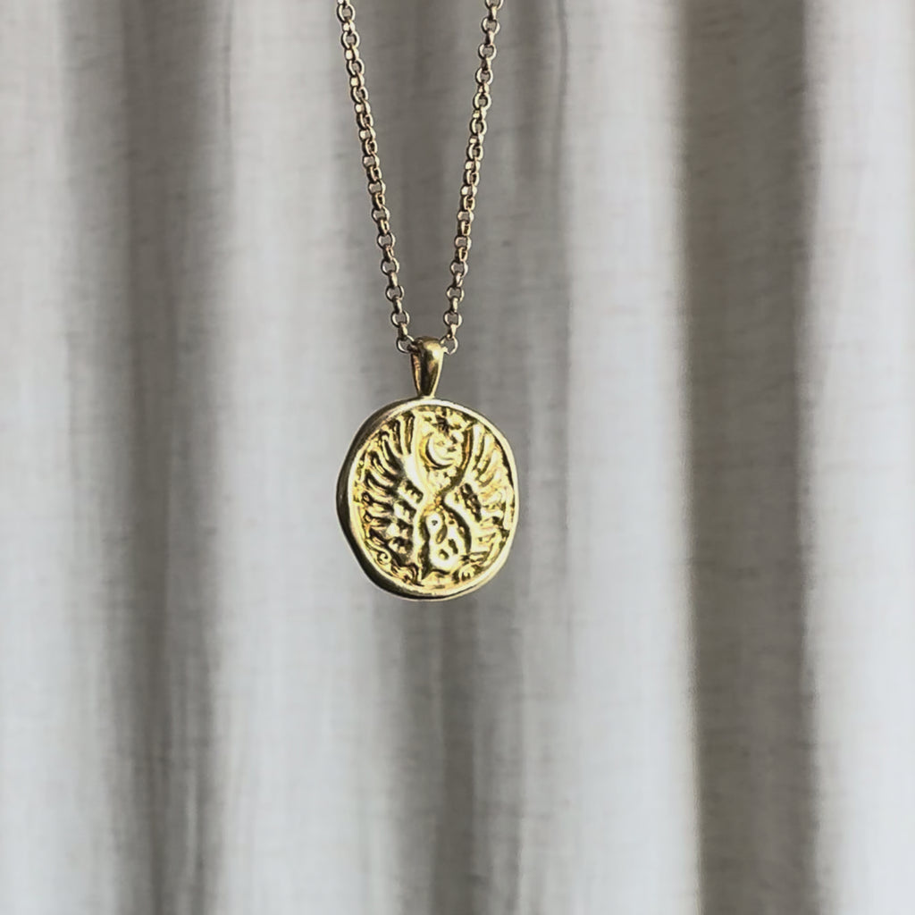 Video of Libra Zodiac Pendant Necklace moving in the sun against a natural fabric background.