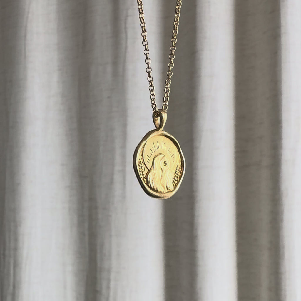 Video of Virgo Zodiac Pendant Necklace moving in the sun against a natural fabric background.