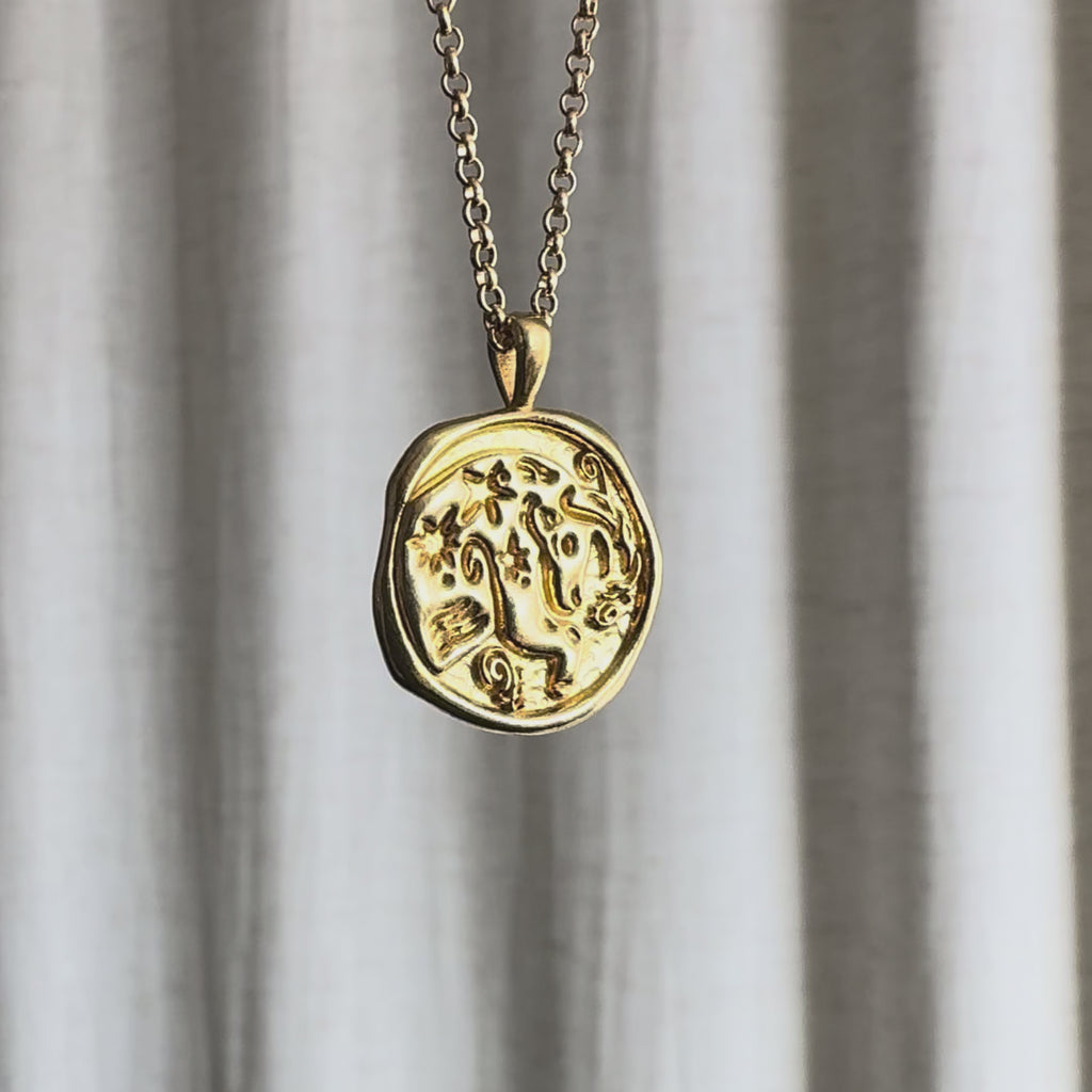 Video of Taurus Zodiac Pendant Necklace moving in the sun against a natural fabric background.