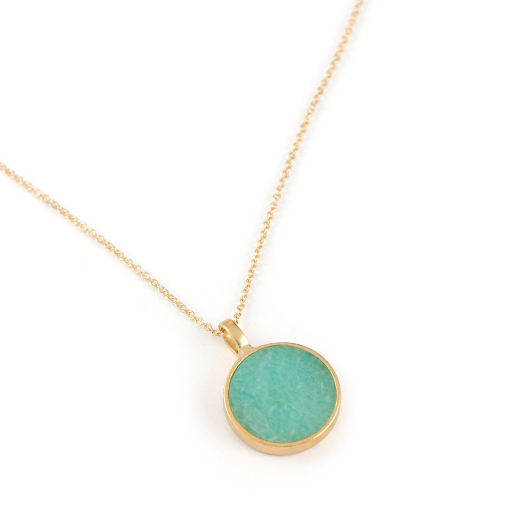 A slice of Amazonite is set in a circular brushed gold vermeil pendant. The turquoise toned pendant hangs on a minimal gold fill chain, styled with a yellow beaded choker necklace.