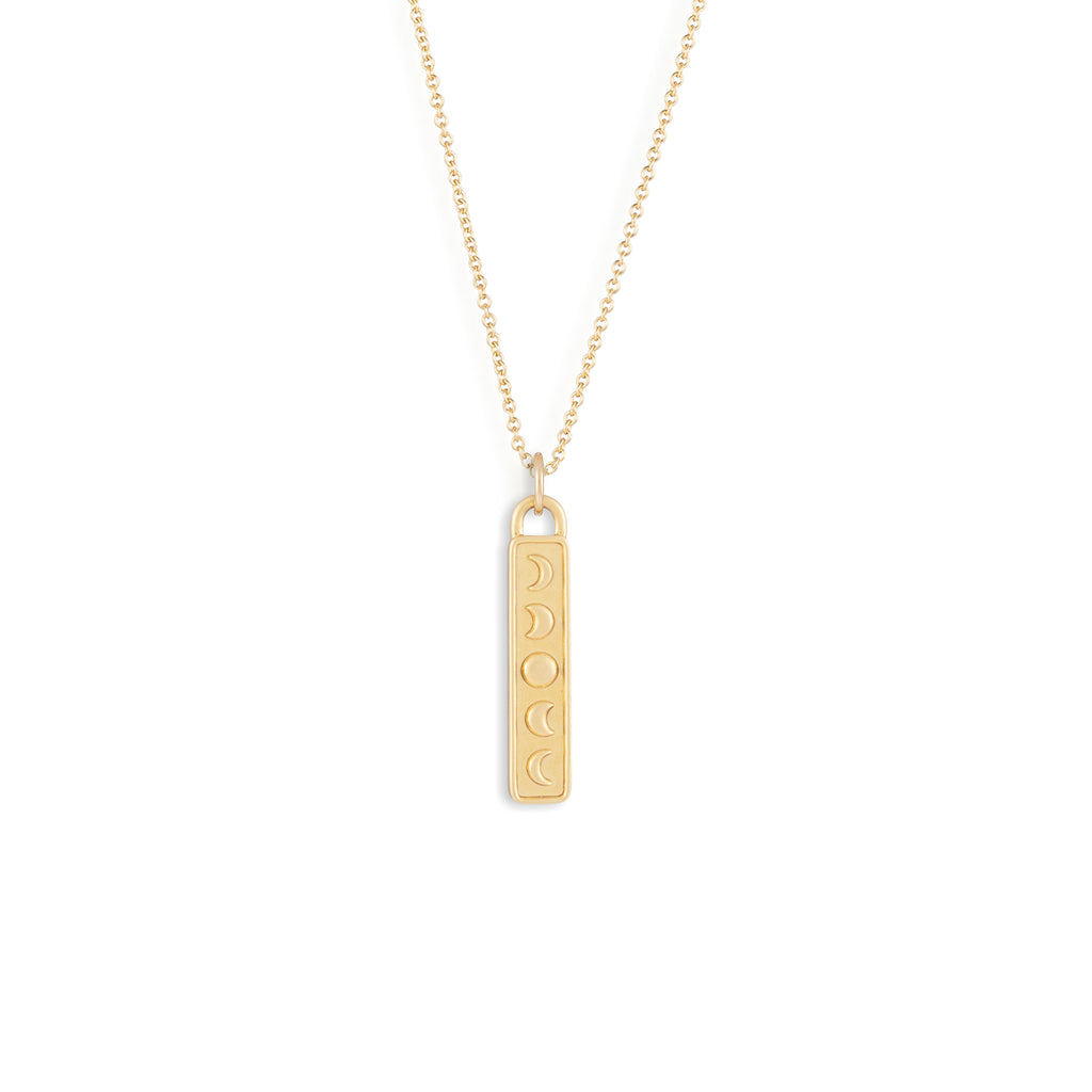 A vertical bar pendant in brushed gold vermeil is adorned with phases of the moon, symbolising the water elemental sign.