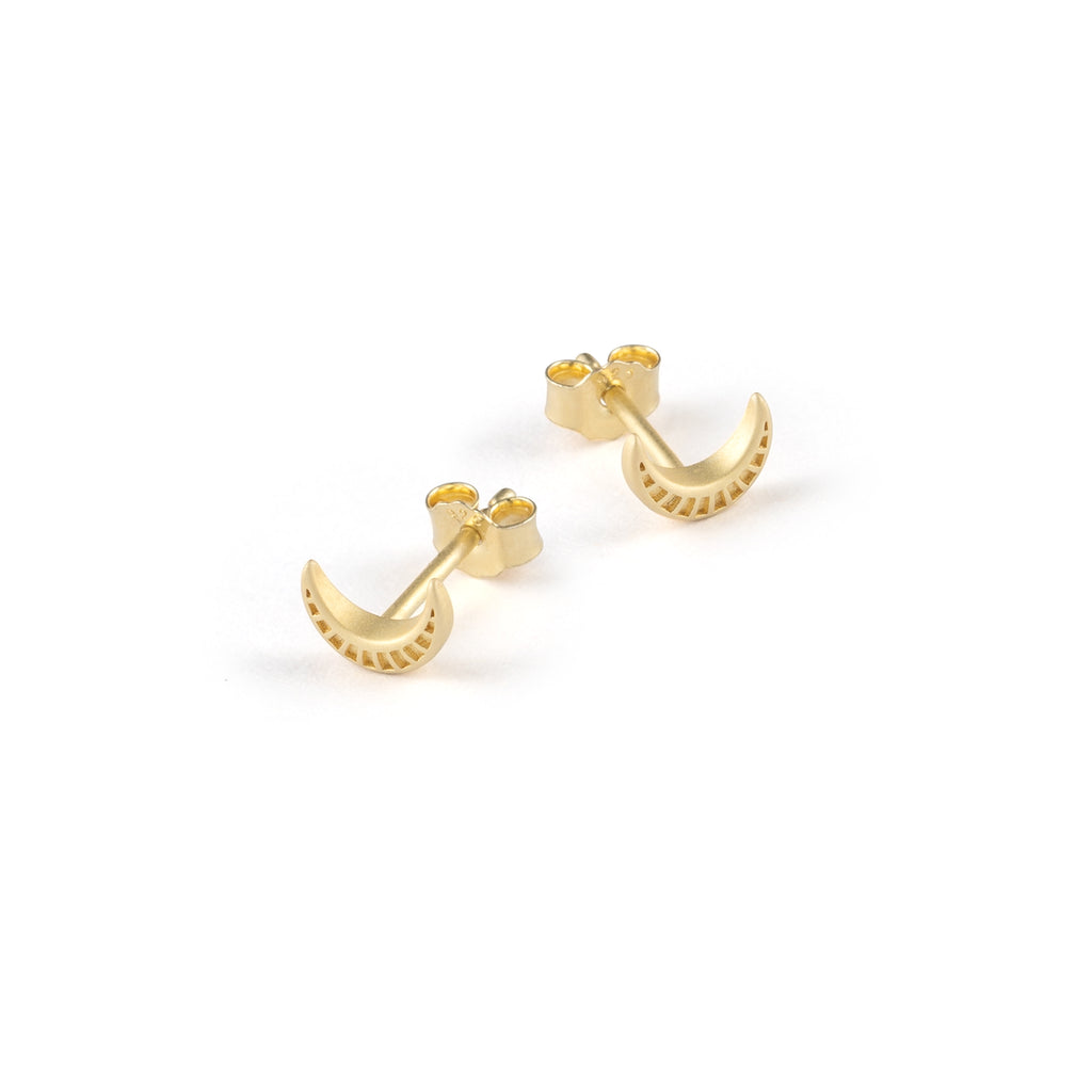 A crescent moon ear stud with tiny rays etched into its surface, capturing and reflecting light with every movement.