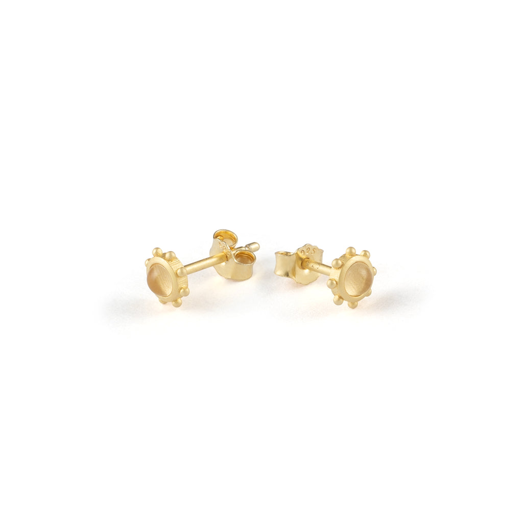 Evoking the design of a ship’s wheel, these dainty circular ear studs feature a quartz cabochon that resembles a porthole bathed in light.
