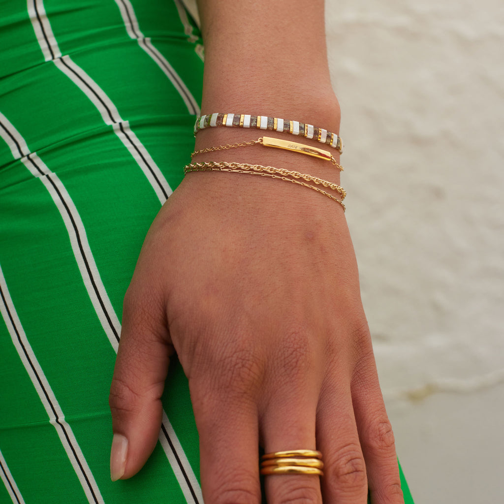 Gold and white beaded bracelet stacked with personalised gold bar bracelet with engraving, and dali gold rope chain bracelet. The Gold Terrazzo Slider Bracelet from our new Laguna collection. Stack  and layer Laguna beaded bracelets to express your own personal style. 