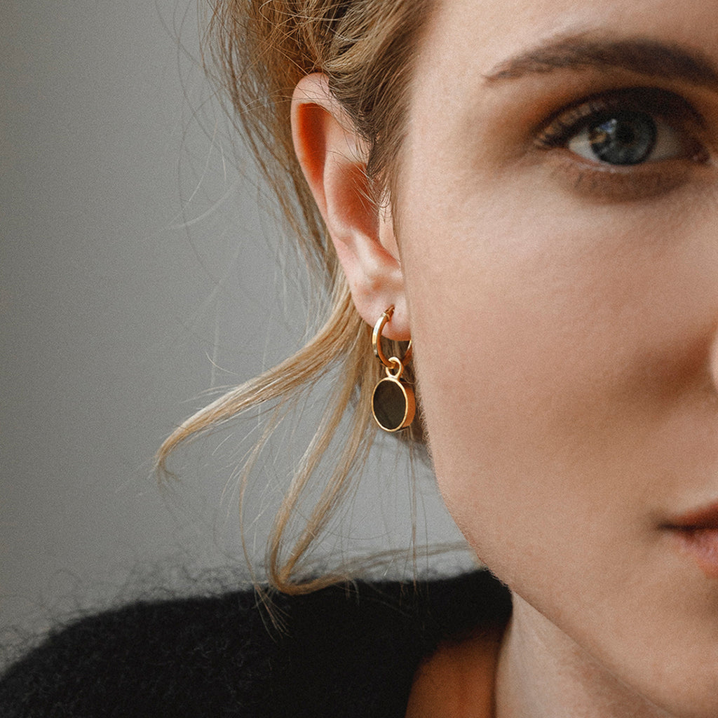 A circle of subtle brushed gold surrounds a black onyx gemstone slice. A minimal, striking gold hoop earring to wear as a pair, or stack them up with other pieces in your earring collection. Proudly designed in Devon & handcrafted by our Wanderlust Life global artisan partners.